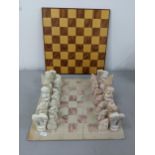 A soapstone chess board having engraved chess pieces, along with a wooden chessboard Location: