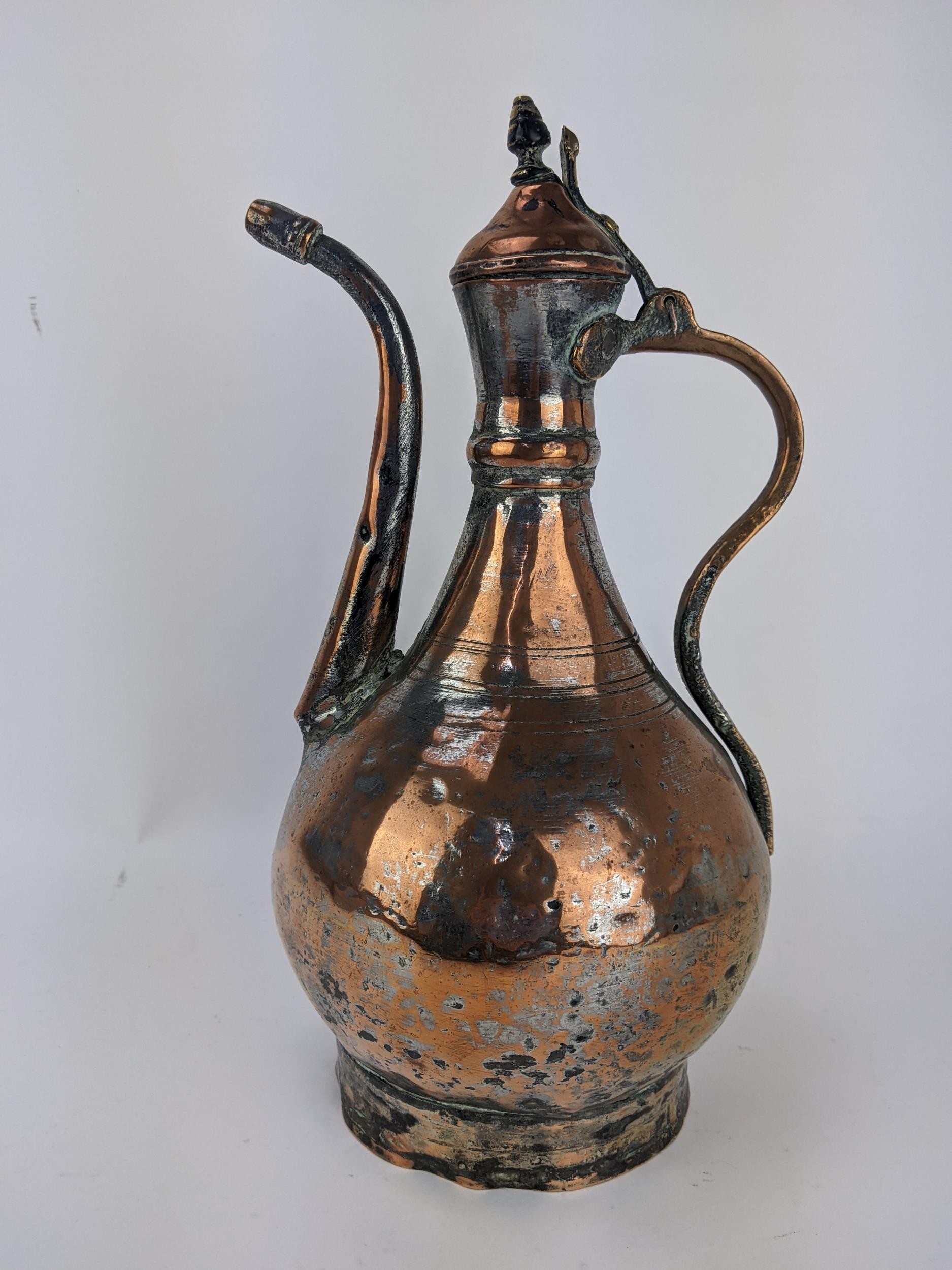 An 18th century Persian copper and brass Dallah, with a hinged lid on curved spout, 36cm high,