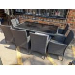 A modern rattan glass topped garden table together with six matching chairs with cushions Location:
