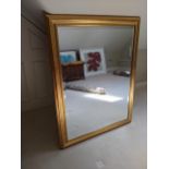 A large bevelled glass mirror with a moulded gilt frame, 135cm high, 96cm wide together with a large