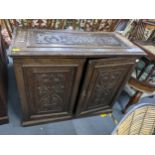 A late 19th/early 20th century oak cabinet having carved panelled top and doors, loose shelves and