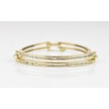 An 18ct yellow gold and diamond bangle, set with two interspersed rows of channel set brilliant