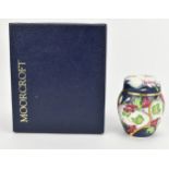 A Moorcroft enamels miniature lidded vase, designed with florals and foliage on a white and dark