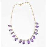 A yellow metal and amethyst fringe necklace, set with graduated faceted oval cut amethyst drops,