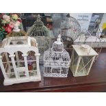 A group of five wirework and white painted wooden conservatory bird cages, flower contained, along