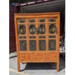 A Chinese black lacquered pine marriage cabinet with four panelled doors decorated with figures