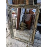 A contemporary silver coloured framed wall mirror, deep swept frame with floral moulded