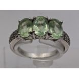 An 18ct white gold three-stone peridot ring with diamond set shoulders 3.5g Location:
