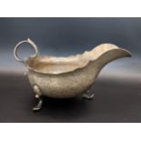 An early 20th century silver sauce boat, having a wavy rim and on three splayed feet, 94.8g