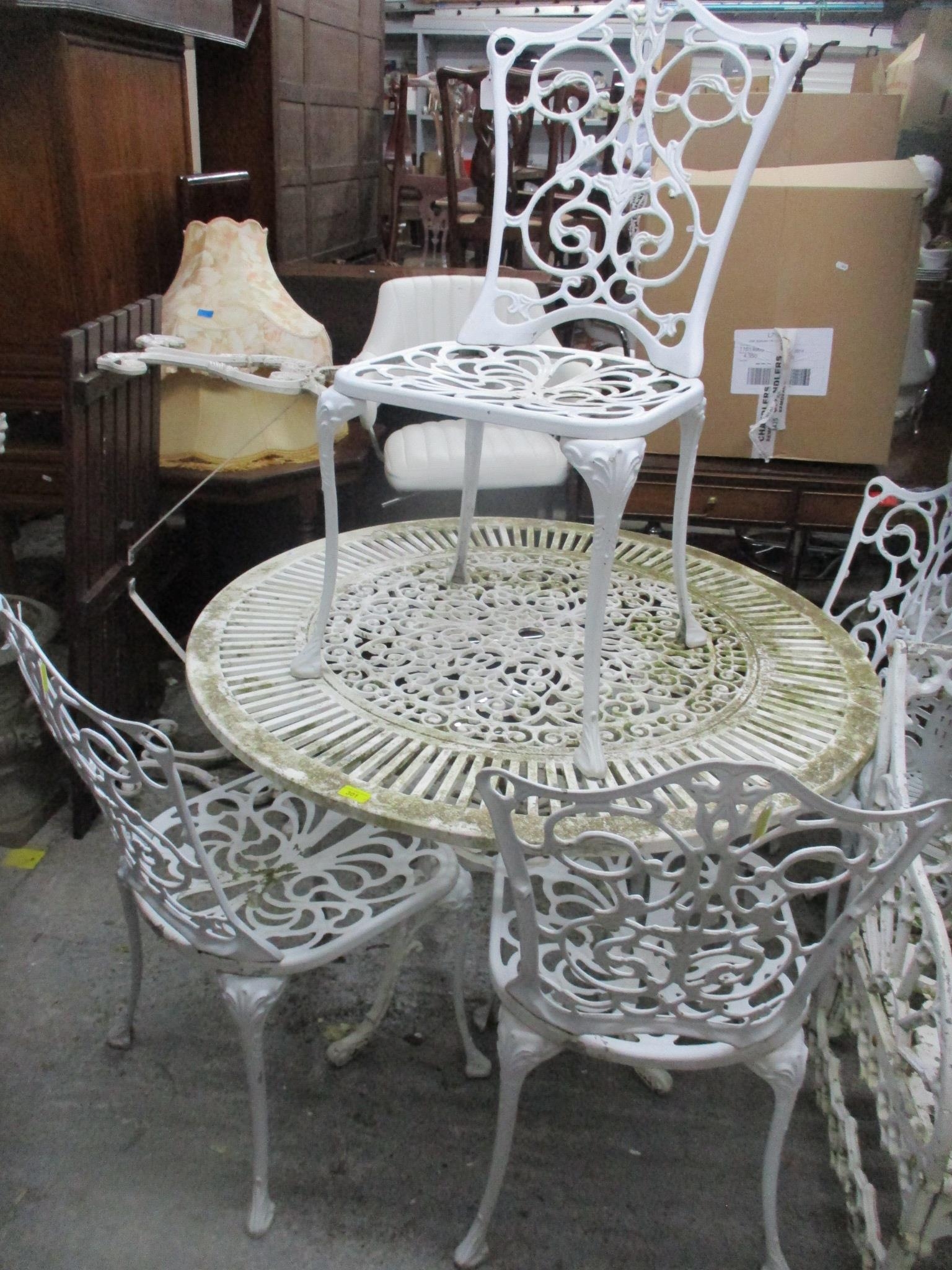A larger white painted aluminium garden table, circular top with space for parasol column, legs