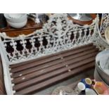 A white painted metal three seater garden bench with wooden slatted seat and a white painted