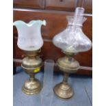 A pair of Victorian brass oil lamps, one having a clear glass shade and the other an etched and