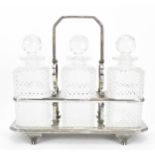 A Victorian silver-plated tantalus, holding three cut glass decanter bottles with faceted