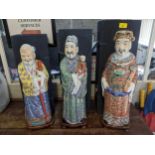 A group of three Chinese porcelain figurines of the Immortals, Fuk, Luk, and Sau, on wooden