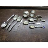 A group of silver items to include three napkin rings, six spoons, one with enamel decoration, and a