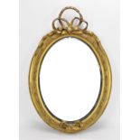 A late 19th century giltwood wall mirror, of oval form with ribbon surmount, the oval plate framed