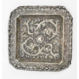 A Chinese export white metal pin dish, circa 1900, of square form with embossed dragons chasing