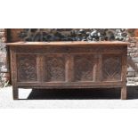 A late 17th century oak coffer, with four carved panel top and foliate carved four panel front on