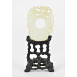 A Chinese carved and pierced white jade plaque on stand, designed with mythical creature and