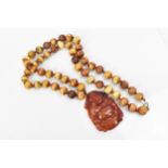 An East Asian carved red jadeite laughing Buddha pendant, on a hardstone prayer bead necklace, the