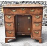 An early George III walnut and feather-banded kneehole desk, the bookmatched veneer top with