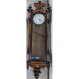 A late 19th century walnut cased Vienna style wall clock with turned finials and enamelled Roman