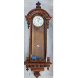 A late 19th century walnut cased Vienna style wall clock with an enamelled dial and Roman