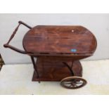 A mid 20th century exotic wood tea trolley with twin full flaps on spoked wheels 70cm h x 84cm w