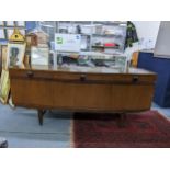 An Elliots of Newbury bow fronted teak sideboard with three drawers over three cupboards on