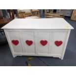 A white painted blanket chest decorated with pink hearts to the panelled front 58cm x 90cm x 48cm