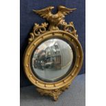 A Regency style convex wall hanging mirror having an eagle surmount, the inner edge with applied