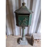 A late Victorian cast iron green painted letter box, the door relief decorated with a figure on
