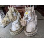 A pair of weathered and painted concrete garden ornaments in the form of horse's heads with double