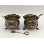 A pair of early 20th century silver salts raised on three feet together with three silver salt