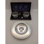 A silver Armada style dish 119.2g, and a pair of glass salts with silver rims, and matching silver