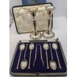 A pair of silver candlesticks, along with a cased set of six silver teaspoons A/F, and sugar tongs