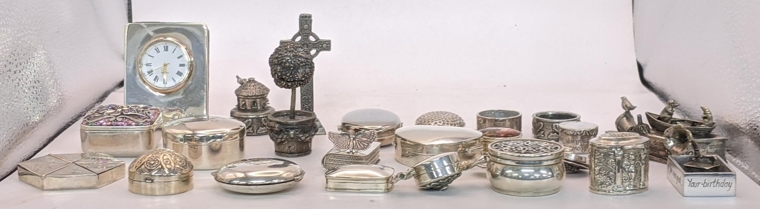 A collection of sterling silver and white metal pill boxes, also including a desk clock on an