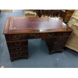 A reproduction mahogany twin pedestal writing desk having a red leather top and nine drawers, 86cm x