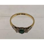 An 18ct gold and platinum ring set with emerald flanked by diamonds, total weight 2.1g Location: