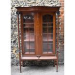 An Edwardian mahogany inlaid display cabinet, with serpentine cornice supported on fluted columns
