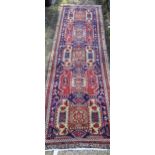 A hand woven Turkish runner having a blue ground, repeating motifs and tasselled ends, 327cm x 109cm