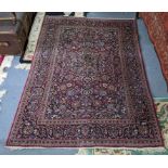 A Persian hand woven Sarouk rug having a red ground and scrolling vines, surrounding a central