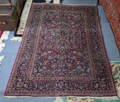 A Persian hand woven Sarouk rug having a red ground and scrolling vines, surrounding a central