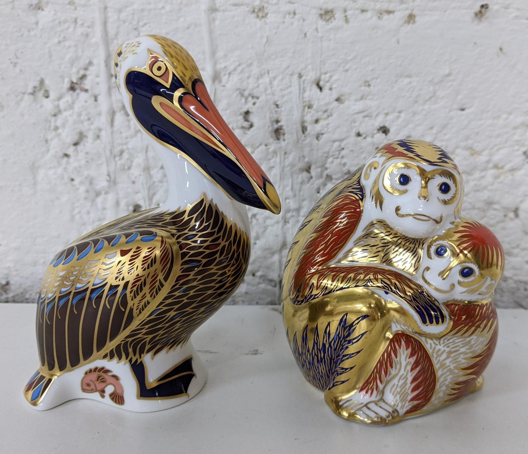 A Royal Crown Derby Pelican paperweight with gold stopper, together with two monkey paperweights