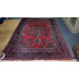 A Persian hand woven rug having a red ground, central motifs and floral design borders, 304 x 200,