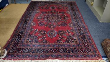 A Persian hand woven rug having a red ground, central motifs and floral design borders, 304 x 200,