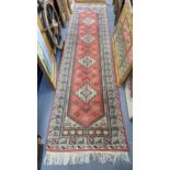 A Turkish hand woven red ground runner having four motifs and a multi guard borders 320 x 82.5