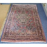 A Persian hand woven, red ground rug having a central motifs, floral design and multiguard