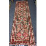 A Kurdish hand woven runner having seven diamond motifs on a red ground, 327 x 96, Location: