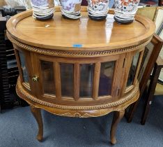 A French style walnut oval cabinet having a beaded border, single door with bevelled glass and on